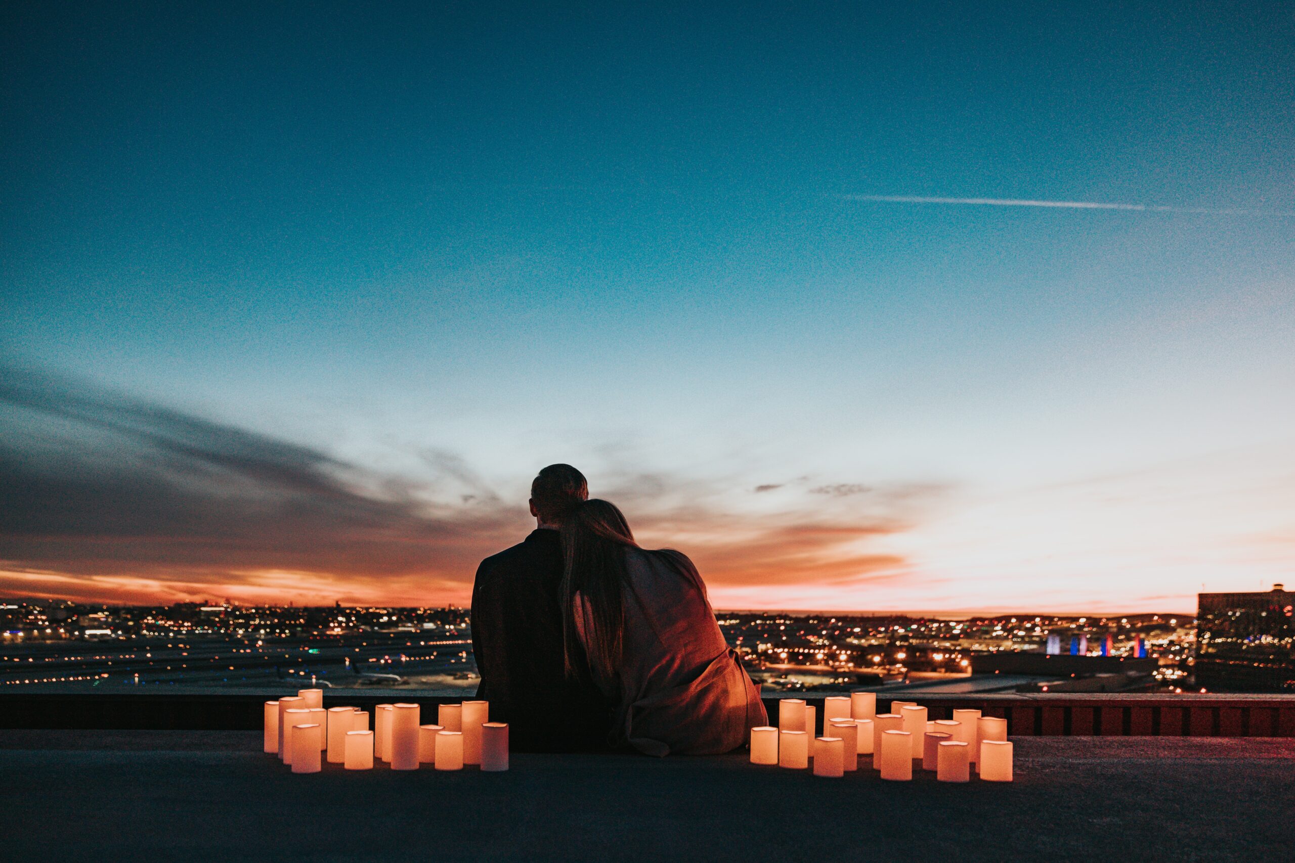 scared of falling in love picture of a couple sitting and looking at a sunset with candles around them