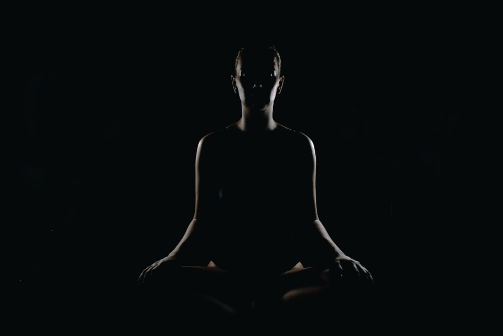 a woman siting in the dark in a lotus position, picture related to the question can psychedelics help with emotional healing