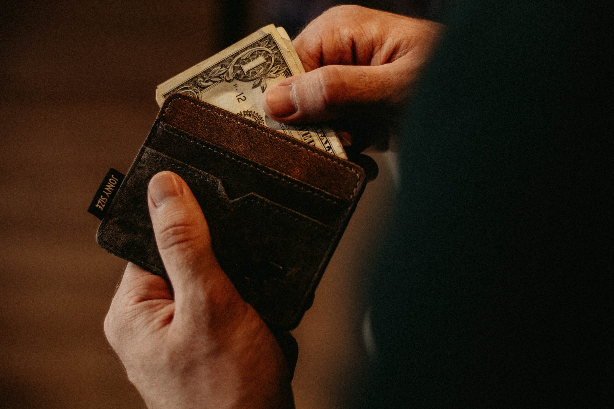 picture of hands holding a wallet and 1 dollar visible, reflecting Journal Prompts for a Money Mindset