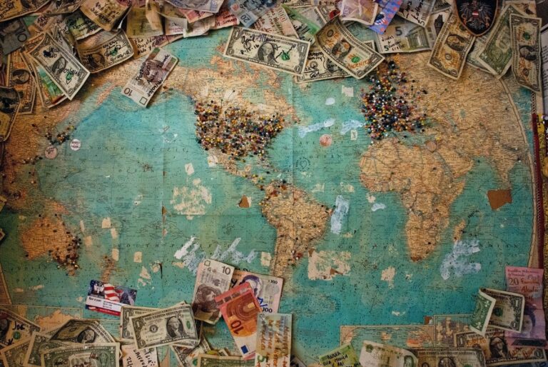 picture with a world map and lots of money around it, representing journaling prompts for money mindset