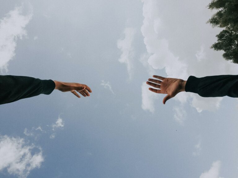 a sky and two hands reaching out to each other