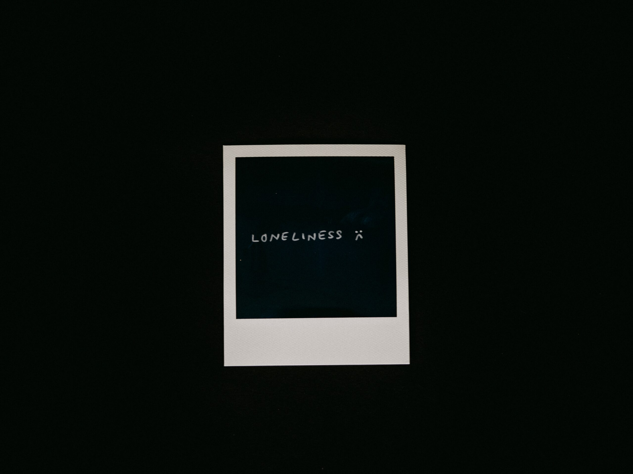 a black polaroid with loneliness written on it, used for article why do i feel so disconnected from everyone